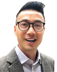 Man wearing glasses and a suit smiling.